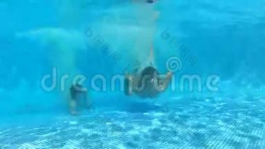两个男孩<strong>跳入</strong>游泳池，然后在水下游到摄像机前